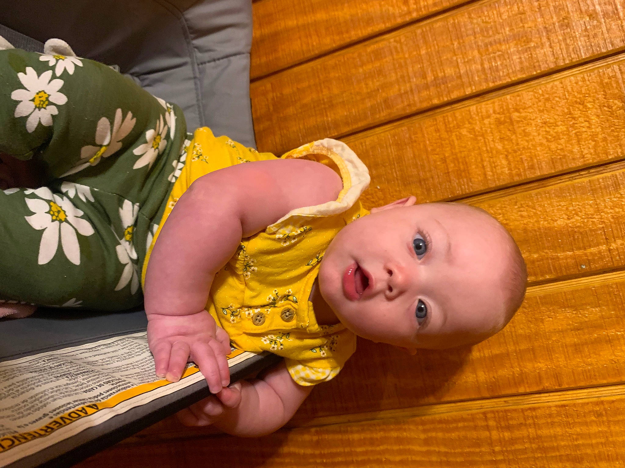 Haden is registered to the contest to win money with this photo: arm, baby, baby_toddler_clothing, cheek, child, comfort, finger, flooring, foot, hand, hardwood, human_body, iris, nose, orange, person, sitting, skin, surprise, toddler