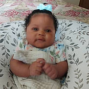 Za'Karrah is registered to the contest to win money with this photo: baby, infant, bow, blanket, cushion, patterned, bedspread, floral, hands, cute, child, indoor, portrait, person, smiling, soft, cozy, comfortable, clothing, relaxing