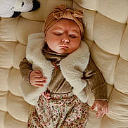 Eva participe au concours pour gagner de l'argent avec cette photo : baby, sleeping, infant, plush, cushion, stuffed_animal, headwear, vest, patterned_clothing, hand, face, indoor, soft_fabric, child, peaceful, cozy, rest, cute, toddler, relaxation