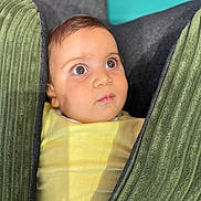 Toma a rejoint le concours — aidez-le/la à gagner de superbes lots ! baby, child, face, eyes, curious, cushion, green, yellow_clothing, indoors, portrait, soft_light, closeup, infant, young_child, seated, expression, texture, fabric, head, skin