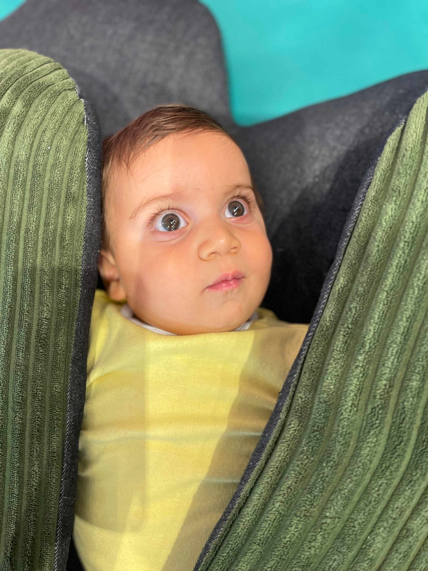 Toma a rejoint le concours — aidez-le/la à gagner de superbes lots ! baby, child, face, eyes, curious, cushion, green, yellow_clothing, indoors, portrait, soft_light, closeup, infant, young_child, seated, expression, texture, fabric, head, skin