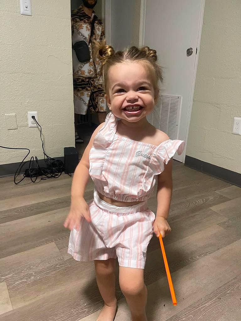 Evelynn is registered to the contest to win money with this photo: baby_toddler_clothing, child, door, dress, event, fashion_design, floor, flooring, fun, happy, human_leg, knee, leg, person, picture_frame, room, smile, toddler, trunk, waist