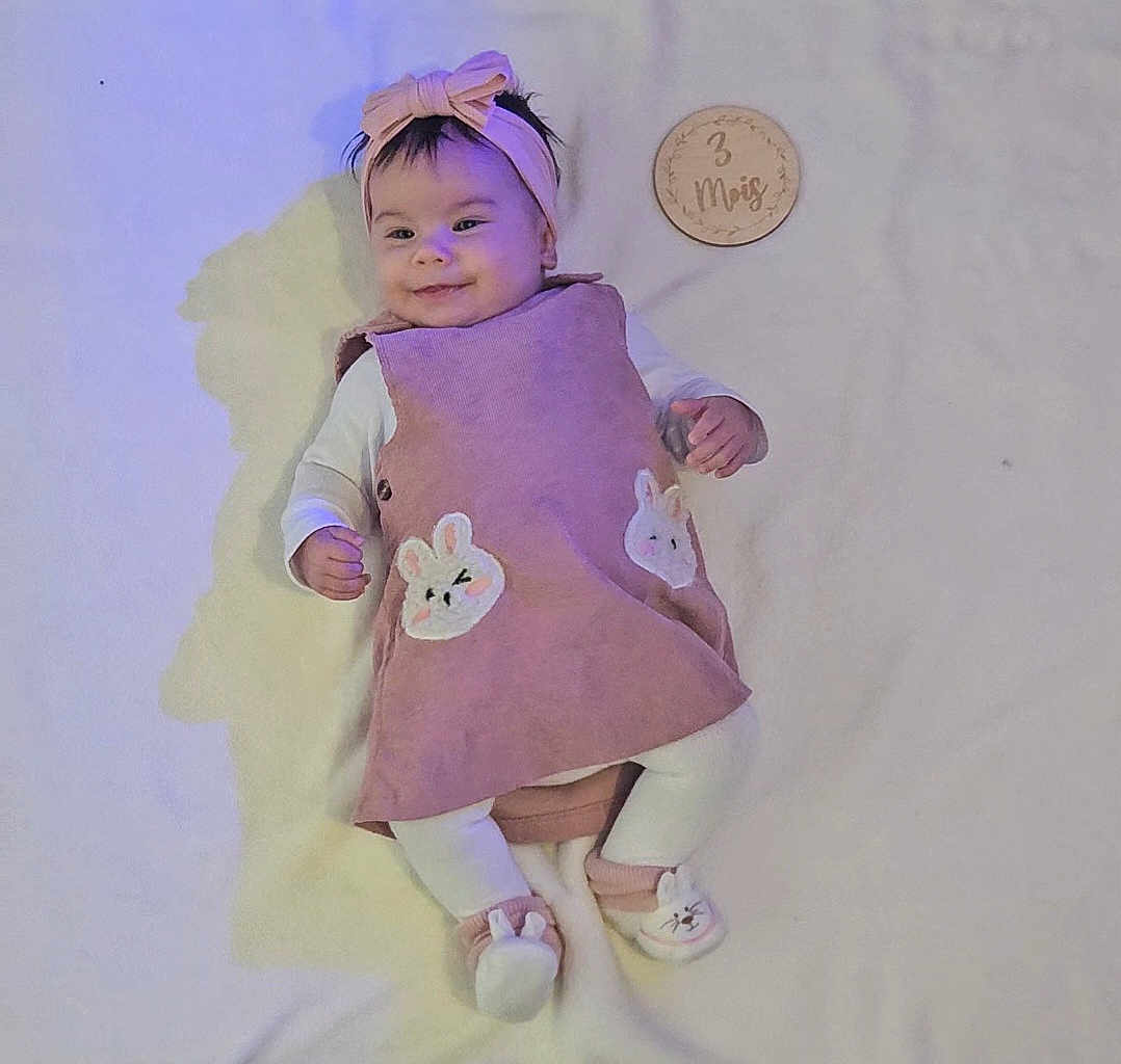 Maria a rejoint le concours — aidez-le/la à gagner de superbes lots ! baby, infant, girl, pink_dress, headband, bunny, slippers, lying_down, blanket, wooden_plaque, milestone, cute, smiling, indoor, soft_lighting, child, portrait, adorable, clothing, baby_accessories