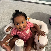 Elizah is registered to the contest to win money with this photo: baby, child, infant, smiling, pink_clothing, curly_hair, inflatable_chair, animal_print, indoor, carpeted_floor, cute, happy, sitting, playful, one_person, young_child, portrait, childcare, baby_toys, home
