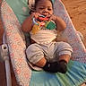 baby, infant, child, smiling, sitting, bouncer, baby_seat, rattle, teething_toy, toy, mickey_mouse, colorful, clothing, shirt, pants, socks, indoor, hardwood_floor, portrait, happy