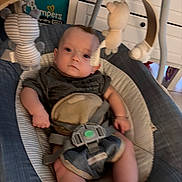 Greyson is registered to the contest to win money with this photo: baby, infant, child, portrait, sitting, bouncer, baby_seat, harness, plush_toy, stuffed_animal, cushion, indoor, home, furniture, drawers, clothing, dark_shirt, bare_legs, serious_expression, photography