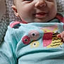 applique, baby, blanket, bodypart, clothing, face, finger, happy, head, knitwear, laughing, newborn, pattern, person, photography, portrait, sitting, smile, sweater, t_shirt