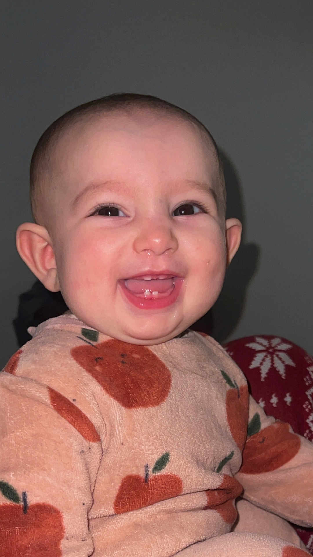 Nour participe au concours pour gagner de l'argent avec cette photo : apple_pattern, baby, cheeks, closeup, drool, ears, eyes, flash, happy, indoor, infant, onesie, pajamas, plain_background, portrait, sitting, skin, smile, toothy_grin, young_child