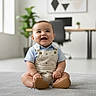 baby, child, smiling, sitting, indoor, carpet, overalls, blue_shirt, modern_room, office_chair, desk, plant, minimalist, happy, cute, portrait, young_child, floor, light, home