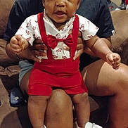 Jaheem joined the competition — help win amazing prizes! baby, child, person, adult, couch, indoor, clothing, red_suspender, bow_tie, white_shoes, legs, hands, wooden_floor, lamp, casual, seated, smiling, curious, home, family