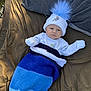 baby, child, hat, pom_pom, blue, blanket, crocheted, clothing, outdoor, mat, denim, face, person, infant, warm, cute, lying_down, winter_wear, expression, cozy