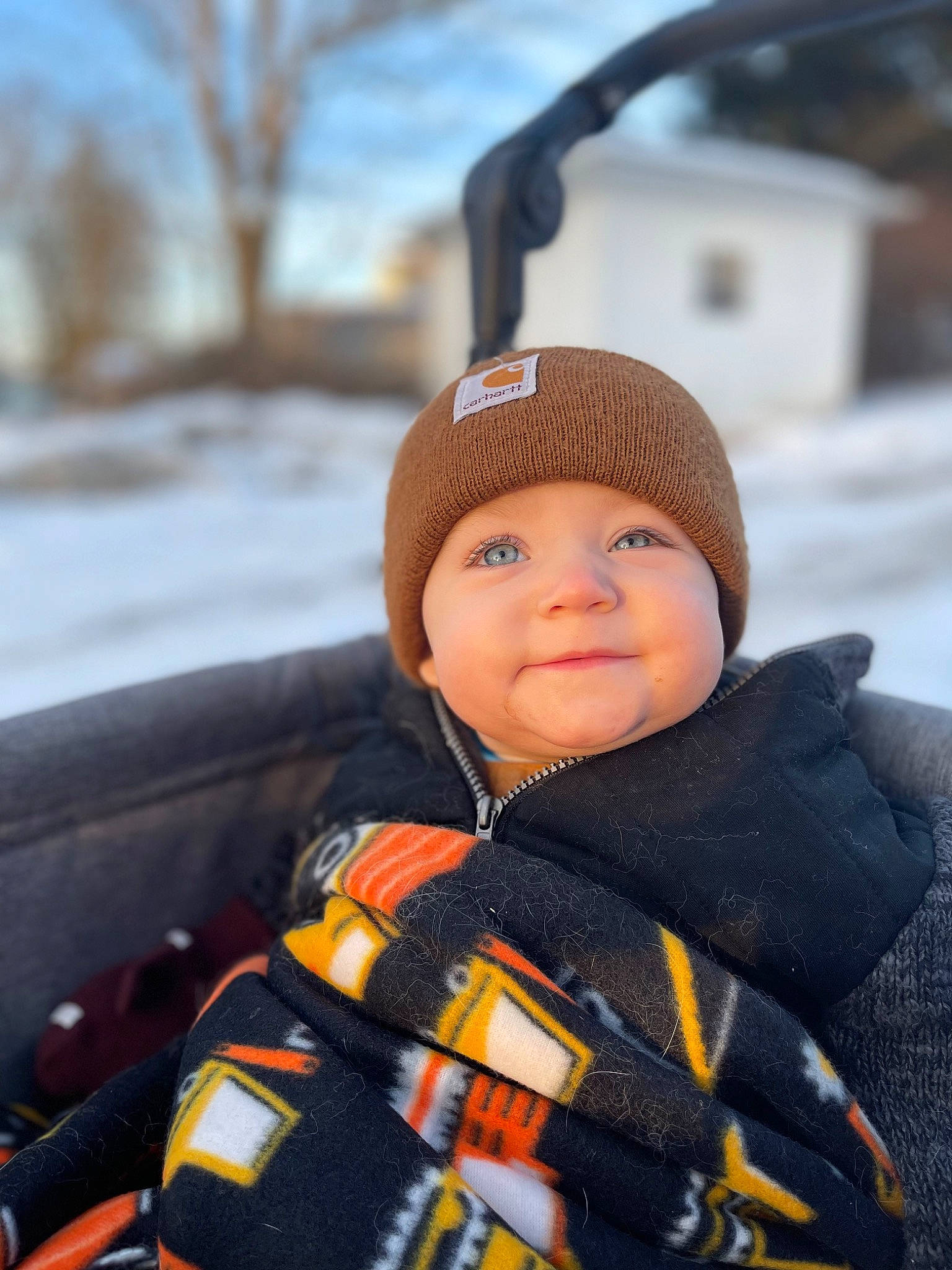 Sawyer is registered to the contest to win money with this photo: automotive_tire, baby, cap, cheek, comfort, face, freezing, headgear, headwear, jacket, knit_cap, outerwear, person, personal_protective_equipment, sky, smile, snow, toddler, tree, winter