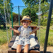 Gennaro participe au concours pour gagner de l'argent avec cette photo : boy, chain, child, cushion, fence, garden, grass, happy, hat, outdoor, playground, shoes, shorts, smiling, socks, sunny, swing, trees, tshirt, wooden_swing