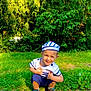 Gennaro participe au concours pour gagner de l'argent avec cette photo : boy, casual_wear, child, crouching, face, grass, greenery, happy, hat, nature, outdoor, park, person, playful, shoes, smiling, striped_clothing, summer, sunlight, tree