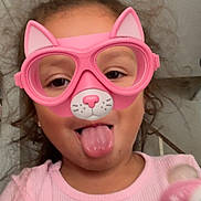 Nayeli joined the competition — help win amazing prizes! child, face, pink, glasses, virtual_filter, cat_ears, tongue_out, pacifier, indoor, curly_hair, playful, person, portrait, silly_face, young, cute, pink_shirt, fun, expression, headshot