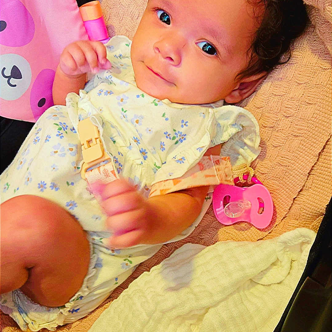 Zorana is registered to the contest to win money with this photo: baby, brown_eyes, chair, child, colorful, cozy, curly_hair, cushion, floral_outfit, indoors, infant, knitted_blanket, pacifier, photography, playtime, portrait, relaxed, sitting, smiling, toy
