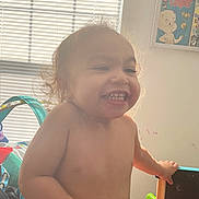 Mason is registered to the contest to win money with this photo: toddler, child, smiling, indoor, window, blinds, toy, play_area, poster, casper, comic, bare_chest, curly_hair, happy, holding, furniture, light, shadow, expression, room