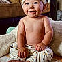baby, child, smiling, sitting, pajamas, hat, indoors, blanket, cute, happy, face, feet, hand, living_room, couch, soft_toys, comfort, portrait, infant, cozy