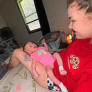 Adalynn joined the competition — help win amazing prizes! adult, baby, crib, family, fan, happy, home, indoor, infant, lying_down, pacifier, person, pink_outfit, portrait, red_shirt, sitting, smiling, socks, tattoo, window