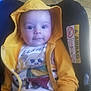 baby, car_seat, casual_clothing, child, comfort, cute, face, footwear, hand, hoodie, indoors, infant, person, portrait, seat, sitting, smile, tiled_floor, yellow_clothing, young_child