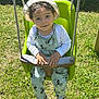 child, clothing, curly_hair, daylight, grass, grass_field, green_swing, happy, leisure, mickey_mouse, outdoor, overalls, person, playground, shoes, smiling, sun_hat, sunny, swing, toddler