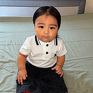 Dylan joined the competition — help win amazing prizes! child, toddler, baby, portrait, sitting, indoors, bed, bedding, white_shirt, black_pants, collared_shirt, fashion, straight_hair, dark_hair, brown_eyes, serious_expression, camera_facing, person, close_up, home
