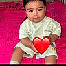 Dylan joined the competition — help win amazing prizes! child, toddler, portrait, sitting, bed, bedroom, pink_bedding, heart_sticker, short_hair, dark_hair, facial_expression, clothing, t_shirt, indoors, home, photograph, social_media, phone_screenshot, baby, person