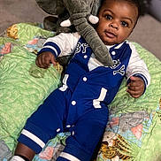 Samorion is registered to the contest to win money with this photo: animal_print, baby, blue_outfit, carpet, child, colorful, cozy, cute, drool, indoor, infant, lying_down, plush_elephant, portrait, quilt, smiling, socks, soft_toy, toy, white_sleeves