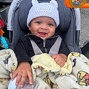 Jasiel is registered to the contest to win money with this photo: baby, blanket, bottle, car_seat, child, clothing, cozy, cute, face, hand, happy, hat, infant, outdoor, person, seatbelt, smiling, toy, transport, warm