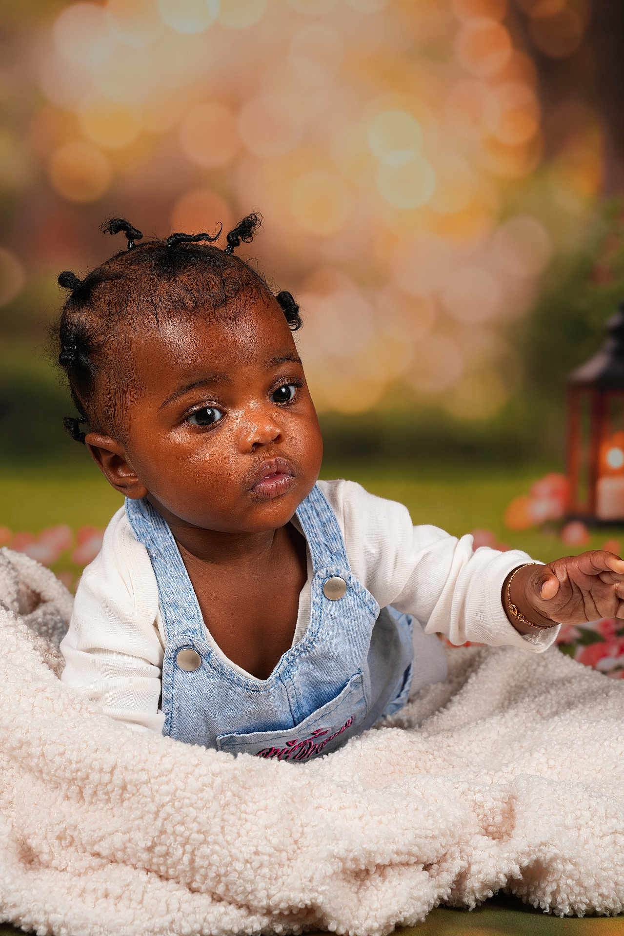 Maëlys a rejoint le concours — aidez-le/la à gagner de superbes lots ! baby, infant, child, blanket, curly_hair, bantu_knots, denim_overalls, white_shirt, portrait, indoor, cute, face, expression, skin, hand, jewelry, bracelet, soft_texture, bokeh, warm_lighting