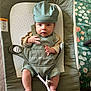 baby, baby_bouncer, baby_delight, bouncer, carpet, child, clothing, cute, fabric, footwear_absent, hat, indoor, infant, looking_at_camera, overalls, pattern, person, seated, small_hands, soft_toys_absent