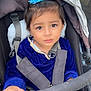 toddler, child, stroller, blue_headband, blue_top, velvet, safety_harness, hand, face, eyes, curious, seat, blanket, indoor, person, baby, portrait, expression, hair, clothing