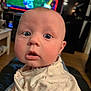 baby, infant, face, eyes, mouth, clothing, floral_pattern, indoor, blurred_background, television, curious, closeup, person, child, cute, soft_lighting, skin, head, expression, wearing