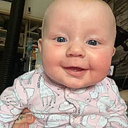 Olivia-Rose is registered to the contest to win money with this photo: baby, smiling, blue_eyes, onesie, animal_print, pink_clothing, hand, tattoo, indoor, sitting, face, child, cute, happy, person, portrait, infant, cozy, home, furniture