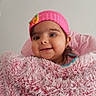 baby, infant, child, smiling, portrait, pink_hat, flower, blanket, fluffy_blanket, chair, indoors, close_up, face, brown_hair, happy, cute, sitting, cozy, photograph, social_media_screenshot