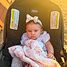 Mackenzie is registered to the contest to win money with this photo: baby, child, car_seat, blanket, headband, bow, outdoor, sunlight, golden_hour, clothing, pink, face, expression, person, infant, sitting, portrait, warm_light, cute, young