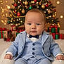 baby, child, blue_suit, bow_tie, christmas_tree, ornaments, lights, presents, holiday, festive, pinecones, portrait, smiling, indoors, cute, celebration, seasonal, happy, sitting, decorations