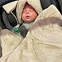 baby, blanket, car_seat, child, sleeping, pacifier, hood, cozy, infant, soft_texture, toddler, indoor, cute, resting, wrapped, warm, face, person, seatbelt, carrying_handle