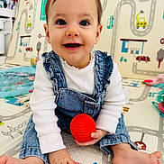 Giulya participe au concours pour gagner de l'argent avec cette photo : baby, child, smiling, play_mat, toy, red_toy, denim_overalls, white_shirt, barefoot, indoor, colorful_background, road_pattern, vehicles, hands, feet, happy, cute, portrait, infant, playtime