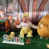 Anna a rejoint le concours — aidez-le/la à gagner de superbes lots ! baby, yellow_outfit, headband, smiling, easter_egg, bunny_figures, spring_sign, green_carpet, decorations, festive, indoor, portrait, child, holiday_theme, cute, colorful, playful, toy_chicken, background, wooden_wall
