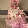 baby, child, pink_bow, headband, sweater, pink_ribbons, tutu, frills, socks, smiling, blue_eyes, couch, indoor, portrait, cute, happy, infant, clothing, fashion, soft_light