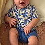 baby, child, blue_eyes, smiling, sitting, shorts, shirt, sandals, patterned_blanket, indoor, happy, cute, infant, hand, footwear, portrait, casual_clothing, skin, face, expression