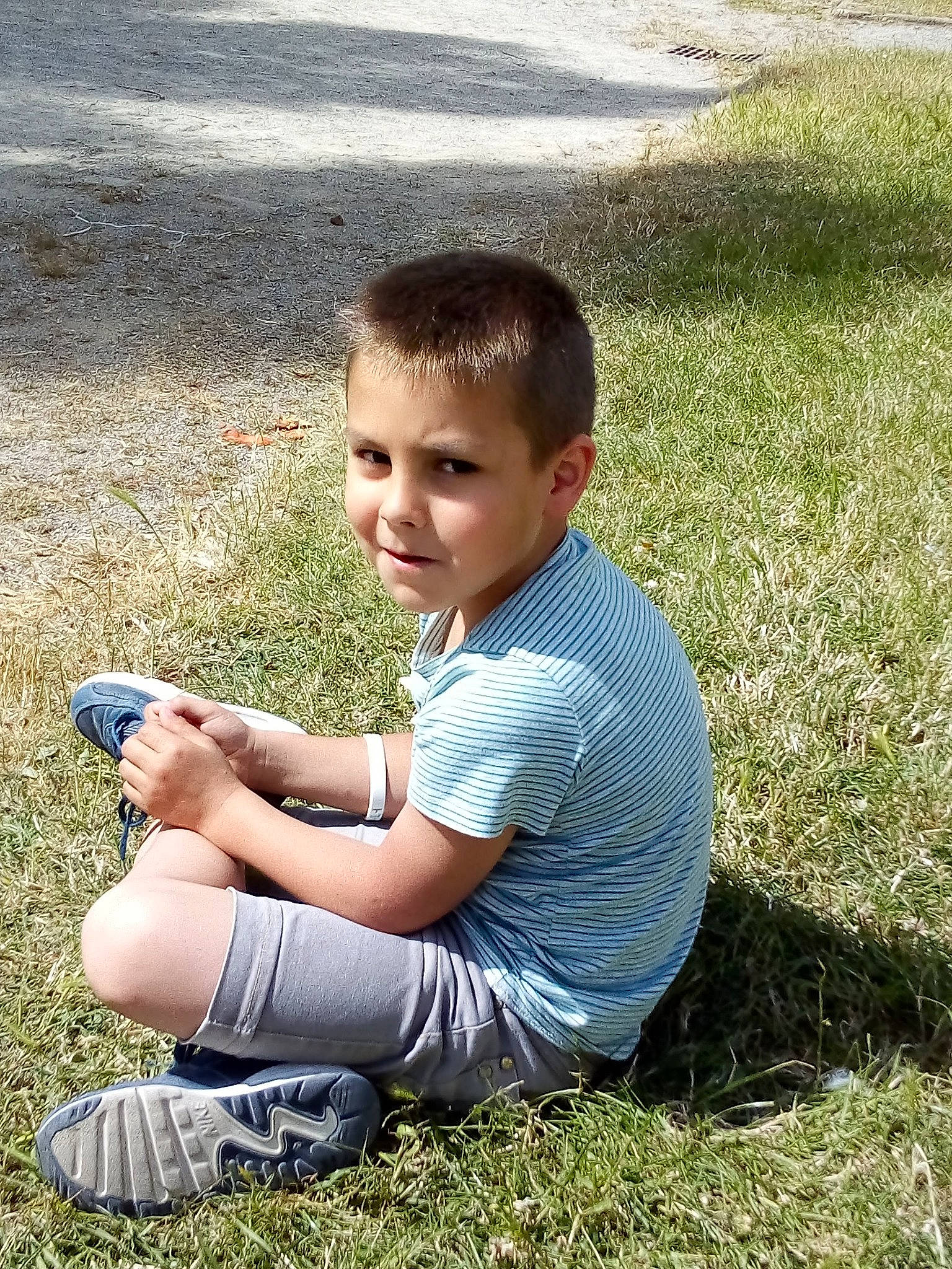 Timotei a rejoint le concours — aidez-le/la à gagner de superbes lots ! arm, clothing, fun, grass, grassland, happy, head, lawn, leg, leisure, meadow, people_in_nature, person, plant, shoe, shorts, sitting, smile, t_shirt, thumb