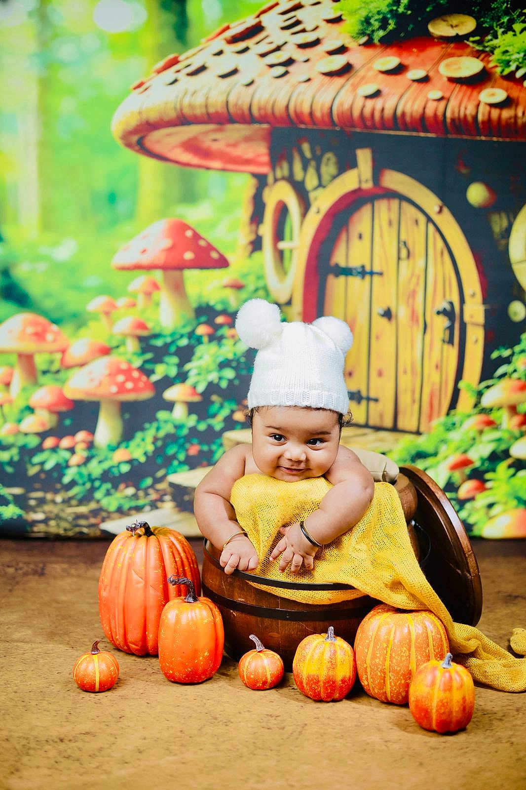 Advik is registered to the contest to win money with this photo: baby, child, pumpkin, hat, bucket, yellow_cloth, mushroom_house, background, autumn, cute, smile, indoors, decorative, orange, wood, playful, festive, portrait, seasonal, fantasy