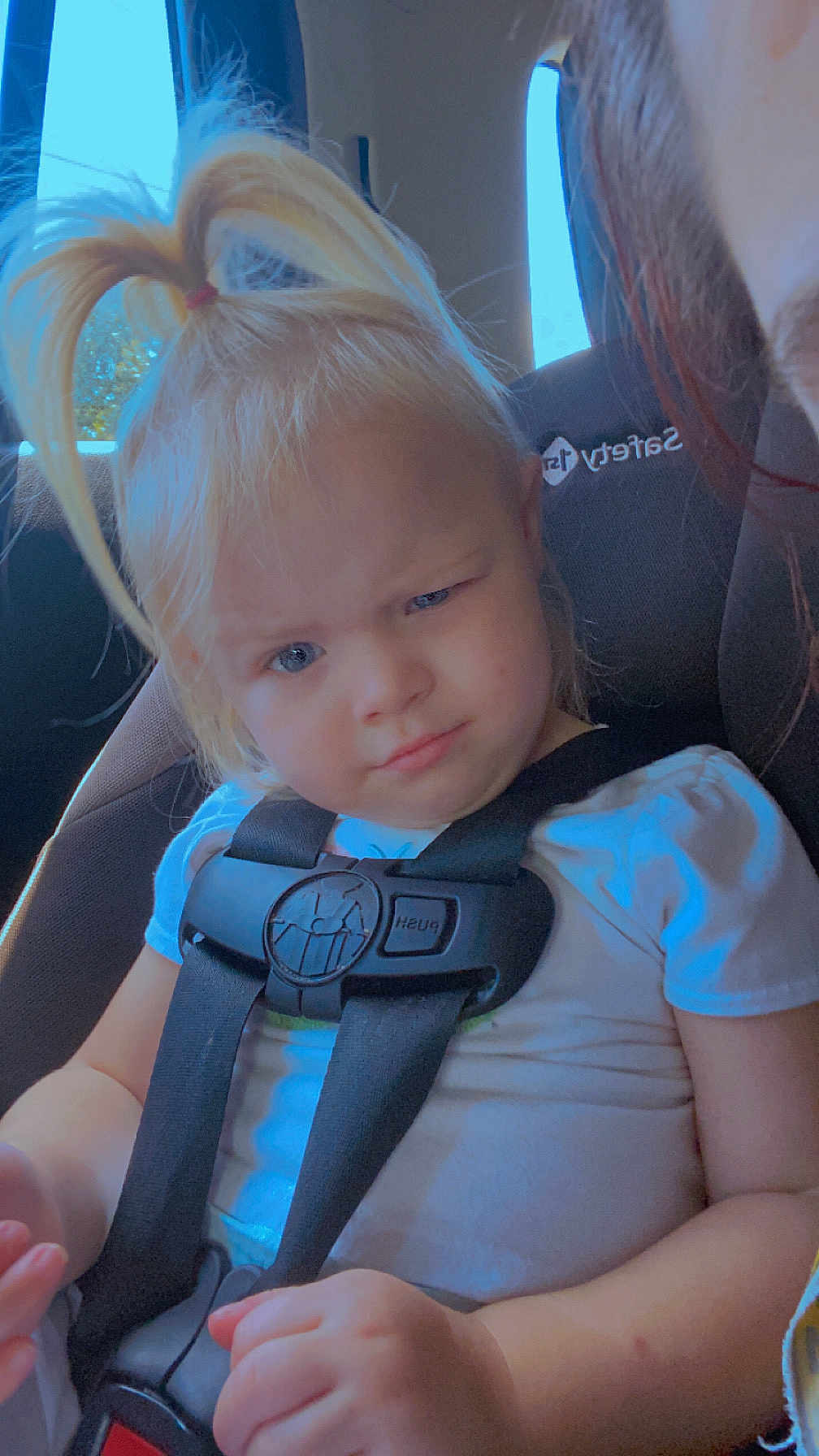 Nova joined the competition — help win amazing prizes! toddler, child, car_seat, seatbelt, blonde_hair, pony_tail, white_shirt, car_interior, window, seat, face, expression, hands, person, safety_harness, young_child, blue_eyes, casual_clothing, travel, vehicle