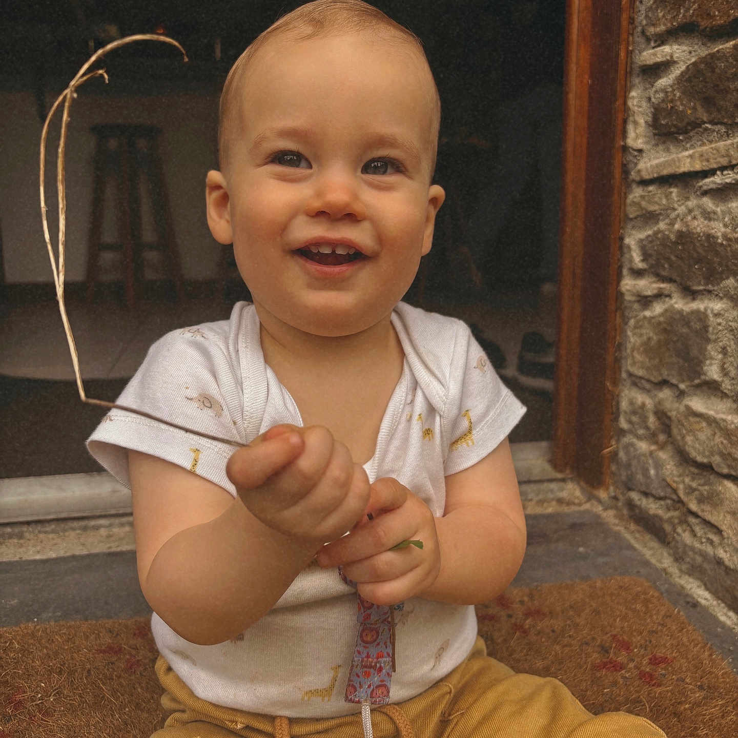 Telio a rejoint le concours — aidez-le/la à gagner de superbes lots ! baby, child, cute, doormat, doorway, eyes, face, hand, happy, indoor, outdoor, pacifier, portrait, sitting, smiling, stone_wall, toddler, twig, white_shirt, yellow_pants
