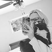 Willow joined the competition — help win amazing prizes! person, cat, mirror, selfie, black_and_white, glasses, smartphone, tuxedo_cat, whiskers, long_hair, ceiling_fan, window, bed, blanket, indoor, hand, sleeve, home, furniture, reflection