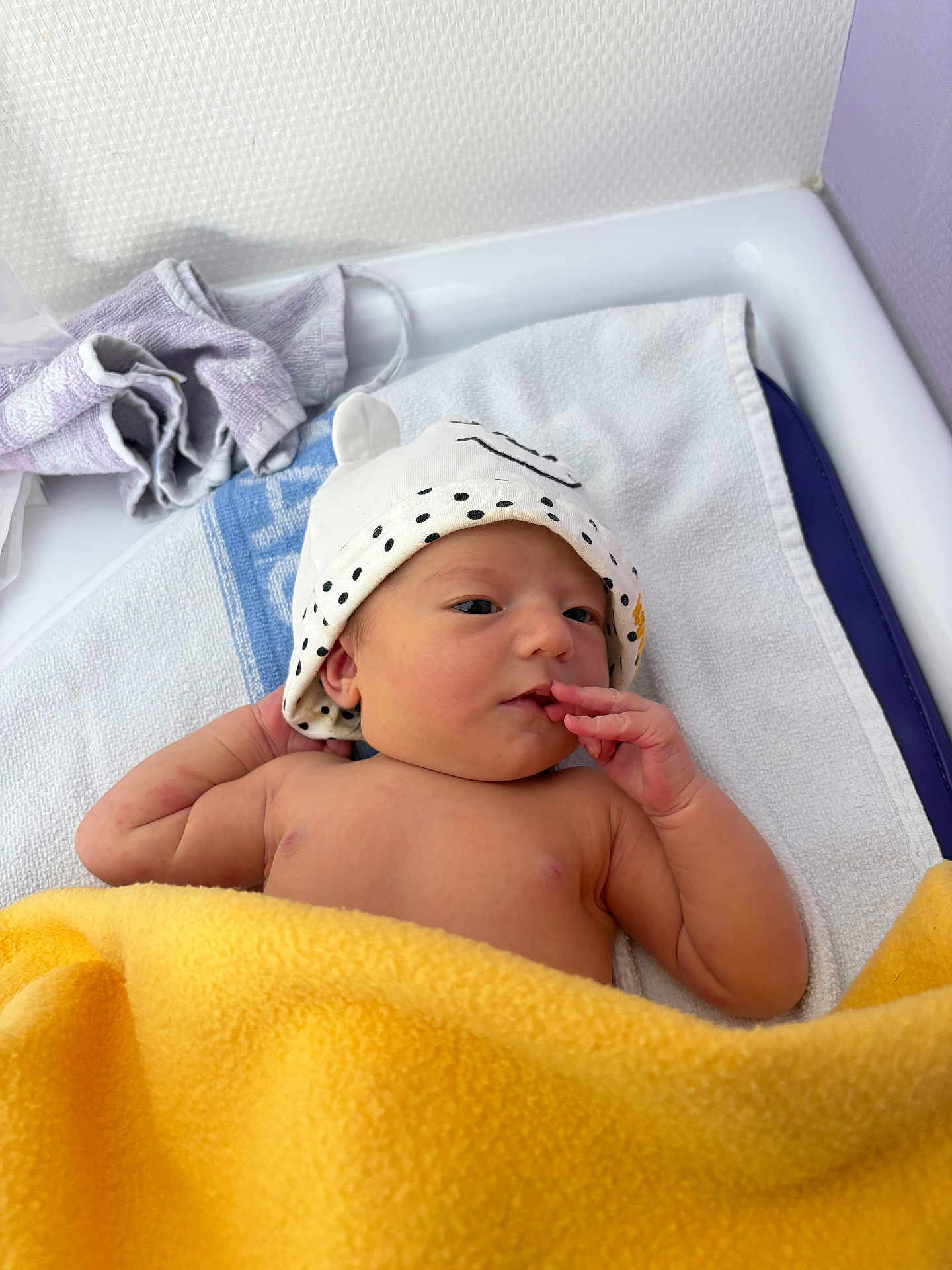 Clémence a rejoint le concours — aidez-le/la à gagner de superbes lots ! baby, newborn, infant, hat, blanket, towel, changing_table, hand, fingers, face, skin, cute, lying_down, nursery, white_towel, yellow_blanket, soft_texture, portrait, cozy, headwear
