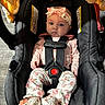 baby, infant, car_seat, floral_headband, pink_clothing, patterned_pants, baby_shoes, seatbelt, child, indoor, portrait, cute, toddler, person, fashion, sitting, adorable, safety, candid, young_child