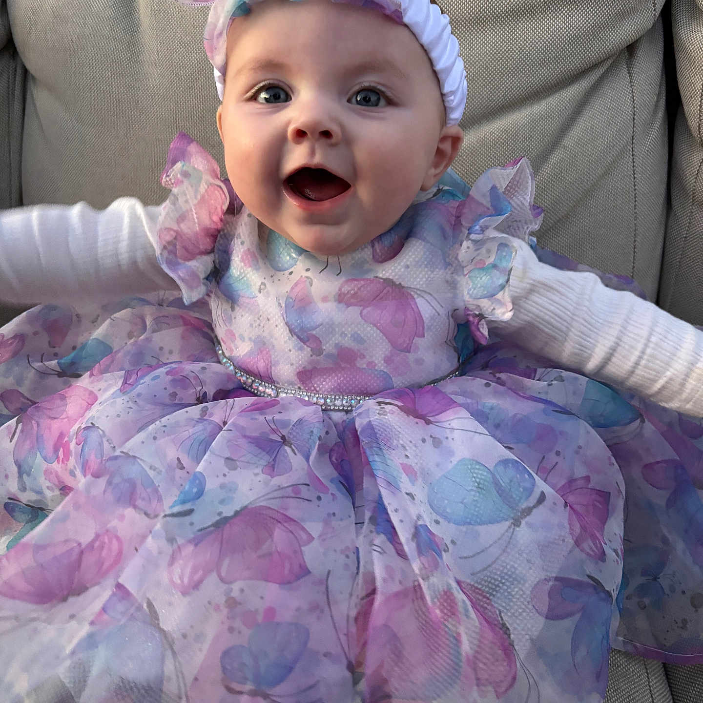Alaina joined the competition — help win amazing prizes! baby, child, smiling, dress, headband, butterfly, purple, blue, pink, sitting, couch, fabric, pattern, happy, cute, portrait, indoors, person, infant, clothing